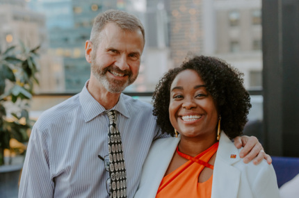 DPA Executive Director Kassandra Frederique and Board Chair Derek Hodel stand together, smiling, at an event.
