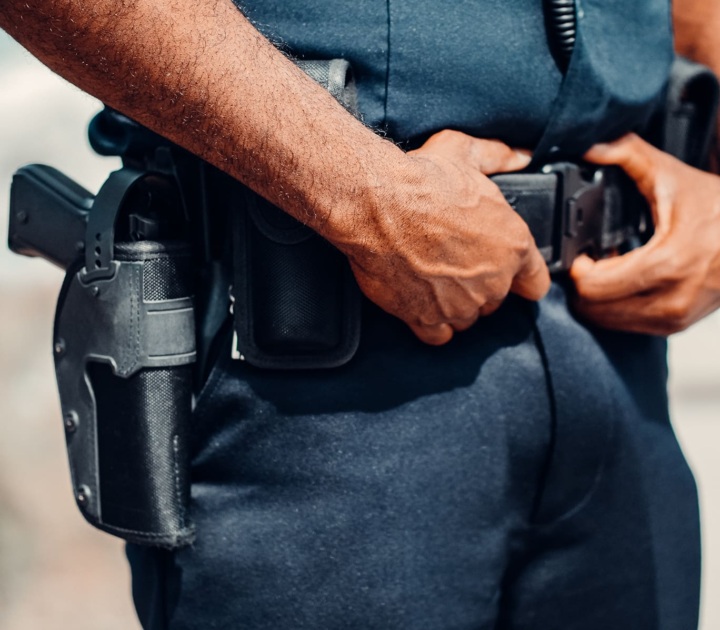 A policeman grabs his belt and we can see his holstered gun.