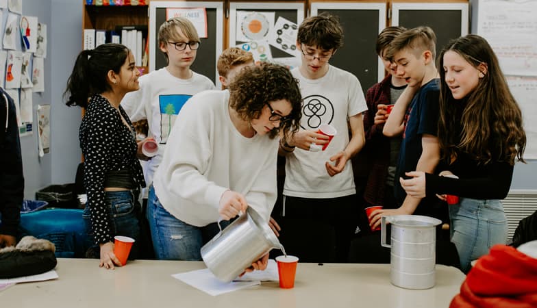 Several high-school aged students are in a classroom engaging in a science project