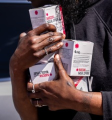 Closeup photo of a person holding multiple boxes of naloxone.