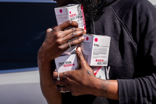 Closeup photo of a person holding multiple boxes of naloxone.